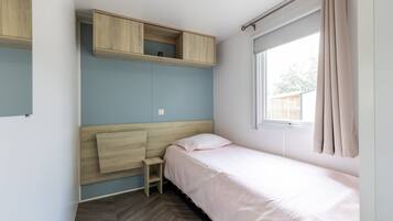 A bedroom with a bed, a desk, and a window.
