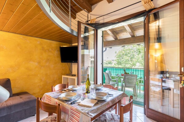 A dining area with a table set for four, a sofa, and a TV on the wall.