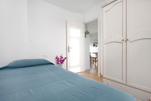 Une chambre à coucher avec un lit, une porte donnant sur une autre pièce et un vase rempli de fleurs.