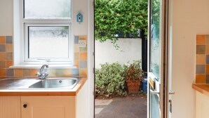 A kitchen with a sink, a window, and a door leading to a garden.