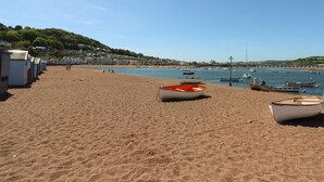 A beach with several boats and a row of beach huts.