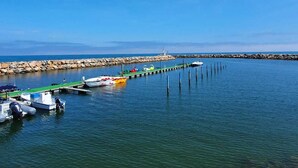 A marina with boats docked, a pier extending into the water, and a rocky shoreline. - Kleines Haus mit Garten, Ideal für Ruhe, Meer, Funboarding und Windsurfing (Le Barcarès)