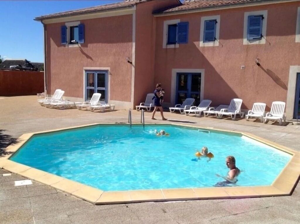 Una piscina con sillas de descanso y un edificio al fondo.