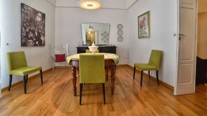 Un comedor con una mesa de madera, cuatro sillas, una araña y adornos en la pared.