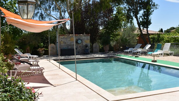 Ein Schwimmbecken mit Liegestühlen und einer Pergola.
