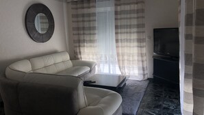 Ein Wohnzimmer mit einer Couch, einem Fernseher und Vorhängen.