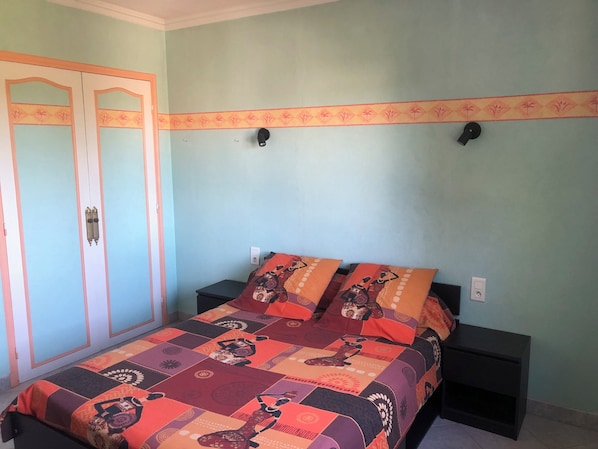A bedroom with a bed, two nightstands, a wardrobe, and a decorative border on the wall.