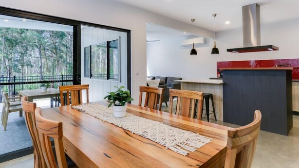 Een moderne eethoek met een houten tafel, stoelen en een potplant.