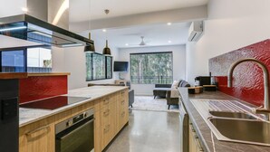 Een moderne keuken met een groot eiland, roestvrijstalen apparatuur en een rode spatwand.