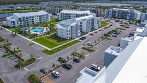 A modern apartment complex with multiple buildings, a central courtyard with a pool, and a parking area. - 205 Luxury condo at Storey lake (Kissimmee)