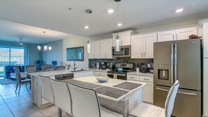 A modern kitchen with white cabinets, stainless steel appliances, and a central island with seating. - 205 Luxury condo at Storey lake (Kissimmee)