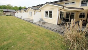 Eine Reihe von einstöckigen Häusern mit Rasengrundstück und einer Terrasse mit Stühlen.