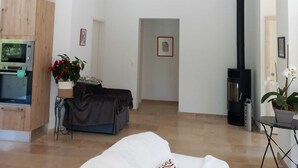 Une pièce spacieuse avec un plafond haut, des poutres apparentes, un lit, un canapé, une petite table avec une plante, une cheminée et un four à micro-ondes.