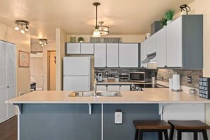 Una cocina moderna con una isla central, electrodomésticos integrados e iluminación colgante.