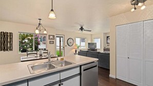 Eine moderne Küche mit Geschirrspüler, ein Essbereich mit Tisch und Stühlen, ein Wohnzimmer mit Sofa und ein großer Kleiderschrank.