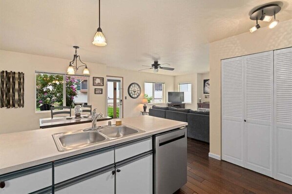 A modern kitchen with a dishwasher, a dining area with a table and chairs, a living room with a sofa, and a large closet.