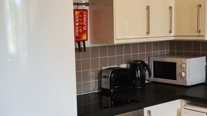 Eine kompakte Küche mit Kühlschrank, Mikrowelle, Toaster, Backofen und Waschmaschine.