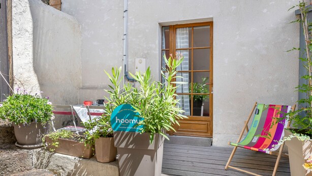 A patio area with potted plants, a wooden deck, and a colorful beach chair. - House in the historic center of Pornic (Pornic)