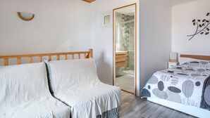 A bedroom with a wooden ceiling, a bed with a patterned bedspread, a bedside table, a nightstand, and a mirror. - House in the historic center of Pornic (Pornic)