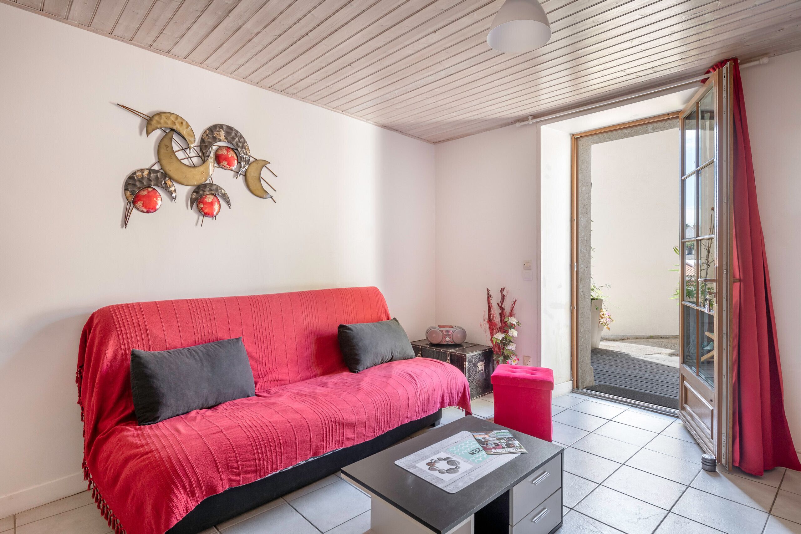 A living room with a red sofa, a coffee table, and a decorative wall piece.