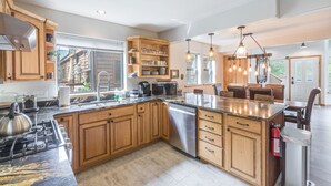 A spacious kitchen with wooden cabinets, a large island, and modern appliances. - Riverwalk Retreat | Private Deck | Walk to Main St (Ouray)