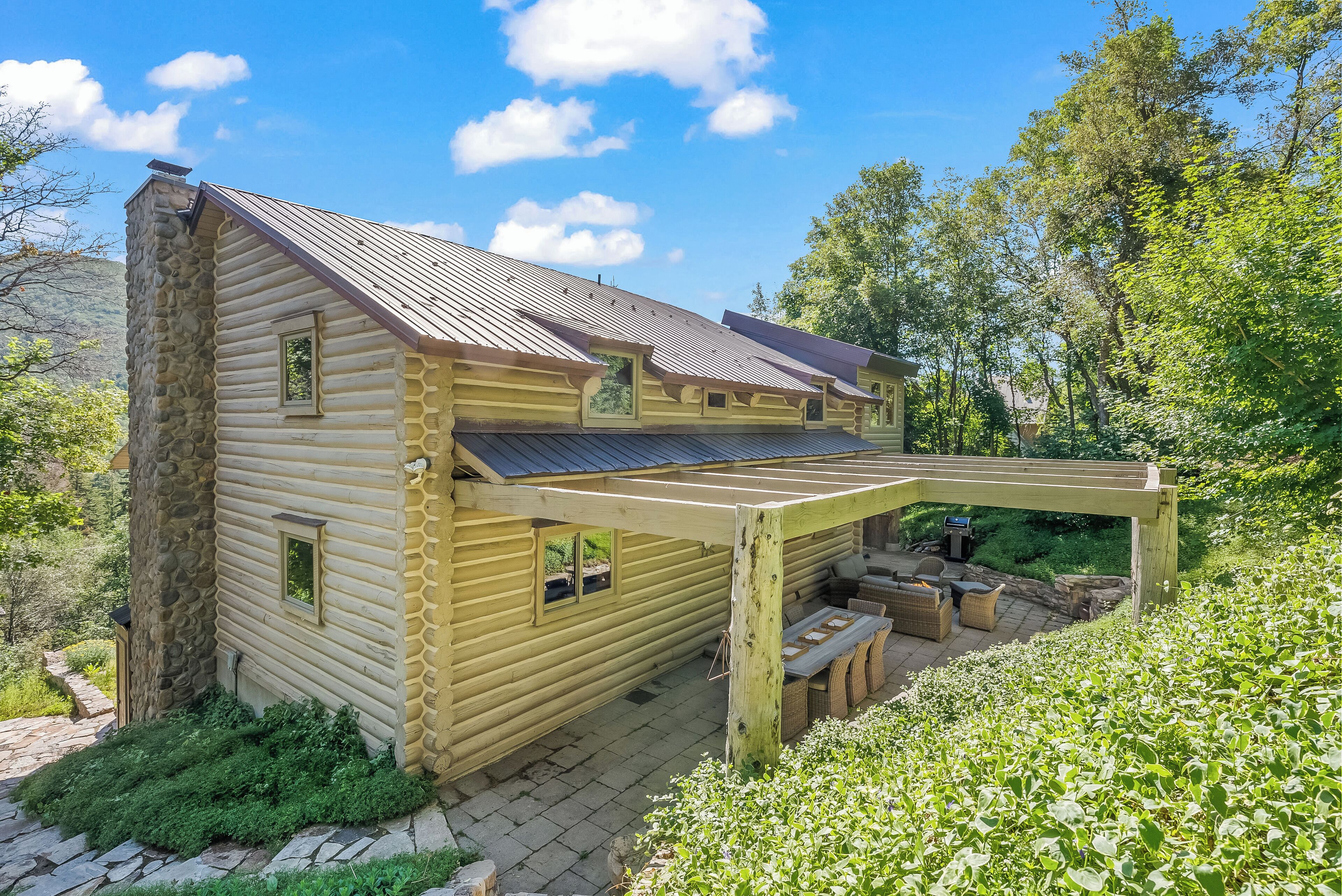 A log cabin with a covered patio and stone walls.