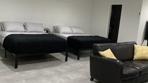 A modern bedroom with two beds, a black leather sofa, and a tiled floor. - Beautiful Miami Pool Lake Studio (Cutler Bay)