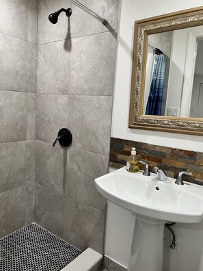 Een badkamer met een douche, een wastafel en een spiegel.