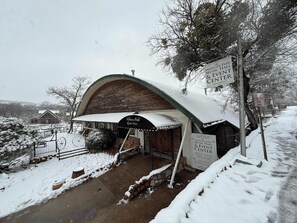 Un edificio cubierto de nieve con un cartel que anuncia el Medicine Park Music Hall & Event Center, indicando que alberga bodas, recepciones, banquetes y eventos corporativos.