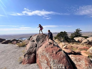 Dos personas de pie sobre una roca grande, con una vista de un paisaje al fondo.