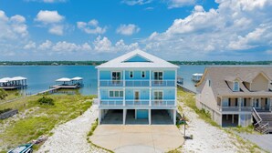 A two-story beachfront house with a balcony, a dock, and a beach view. - Luxury Lagoon Front Retreat | Private Pool | Pier and Beach Access (Gulf Shores)