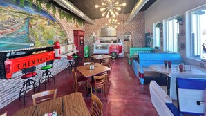 Interior de restaurante con un letrero de Chevrolet antiguo, paredes de ladrillo y un mural.