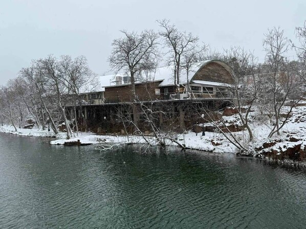 Ein Gebäude mit einer großen Bogenstruktur, einem flachen Dach und einem Wasserspiegel im Vordergrund.
