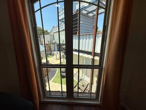 A window with a view of a residential area, including a house and a street.