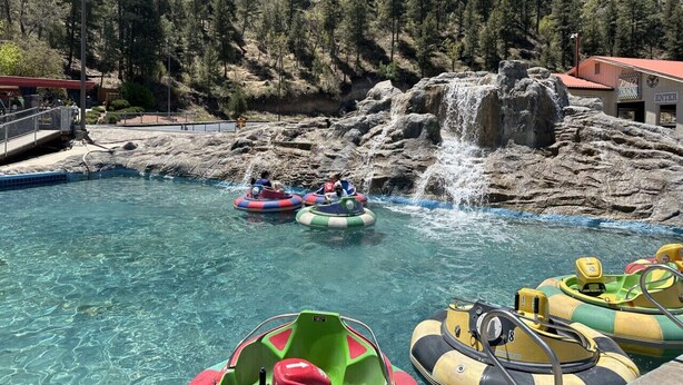 Un parco acquatico con piscina trasparente, zattere gonfiabili e una cascata.