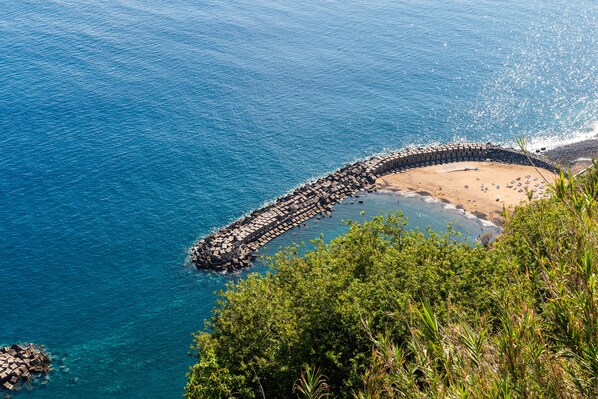Enjoy a serene seaside escape with a sheltered beach area and lush green surroundings.