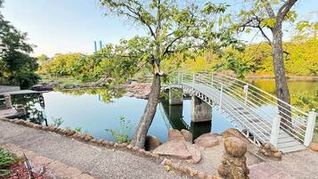 A bridge over a calm water body with a stone pathway and trees.