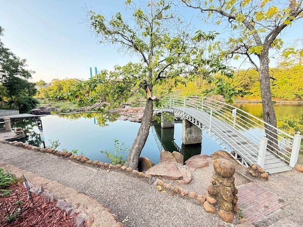 A bridge over a calm water body with a stone pathway and trees.