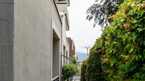 Ein schmaler Ziegelweg, der von einer niedrigen Hecke und einem modernen Gebäude mit flacher Fassade gesäumt wird.