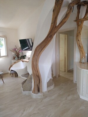 A modern interior with a unique wooden staircase, a white bathtub, and a flat-screen TV. - Villa Giorgia – Sardinia, Orosei: An Entire House with Views of the Valley and the Sea (Orosei)