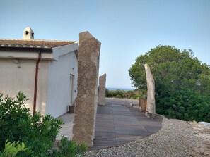 A pathway leading to a building with a tiled roof and a stone pillar. - Villa Giorgia – Sardinia, Orosei: An Entire House with Views of the Valley and the Sea (Orosei)