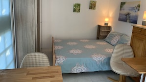 Een slaapkamer met een bed, twee nachtkastjes met lampen, een houten bureau, een stoel en een kledingkast.