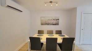 Un comedor con una mesa y sillas, un aplique de techo y una puerta.