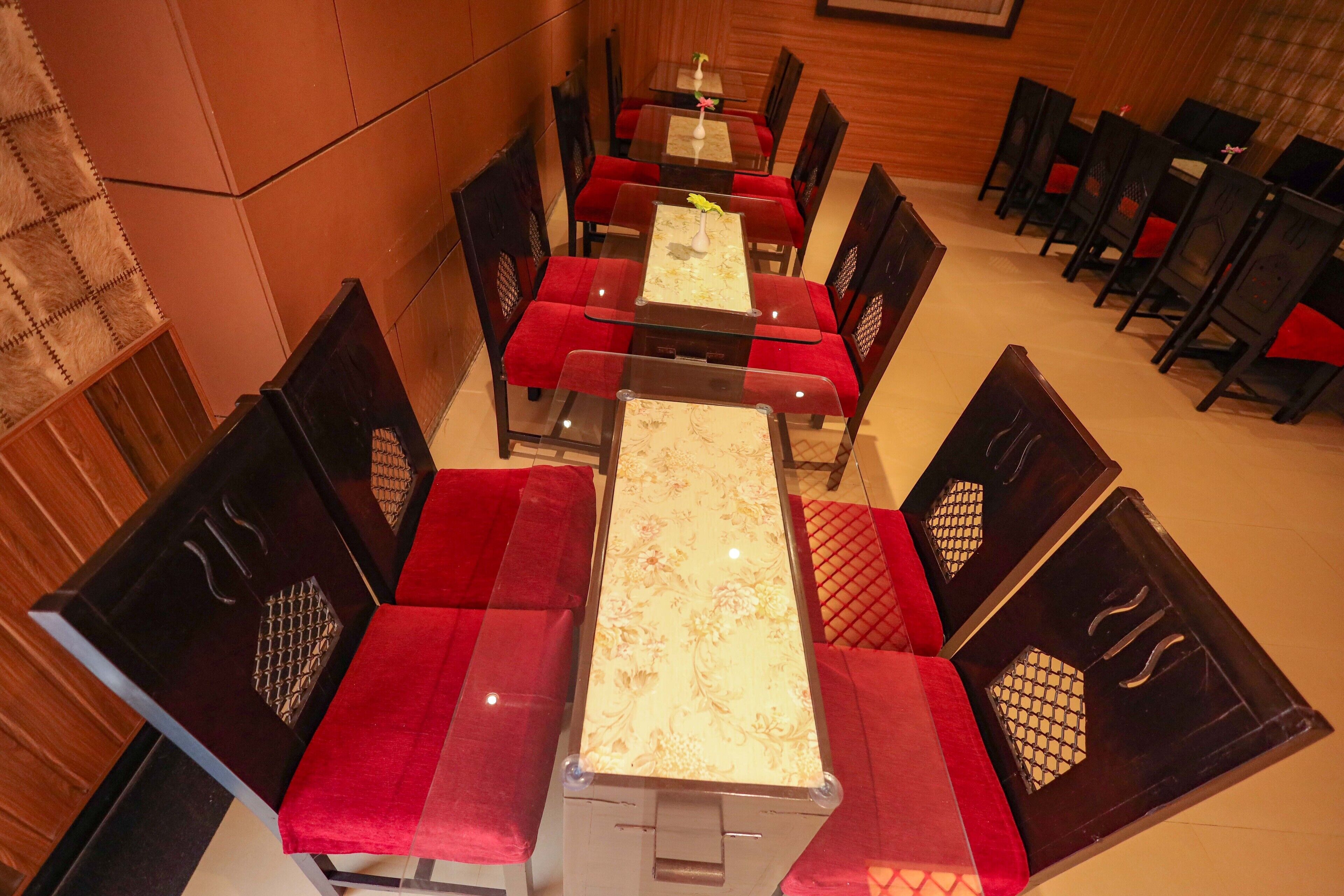 A dining area with a long table and red cushioned chairs.