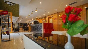 A hotel reception area with a marble counter, a red seating area, and a wall-mounted sign for 'The Times of India'. - Maru Casa A City Center Hotel (Jaipur)