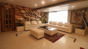 A modern living room with a sofa set, a coffee table, and a decorative wall mural. - Maru Casa A City Center Hotel (Jaipur)