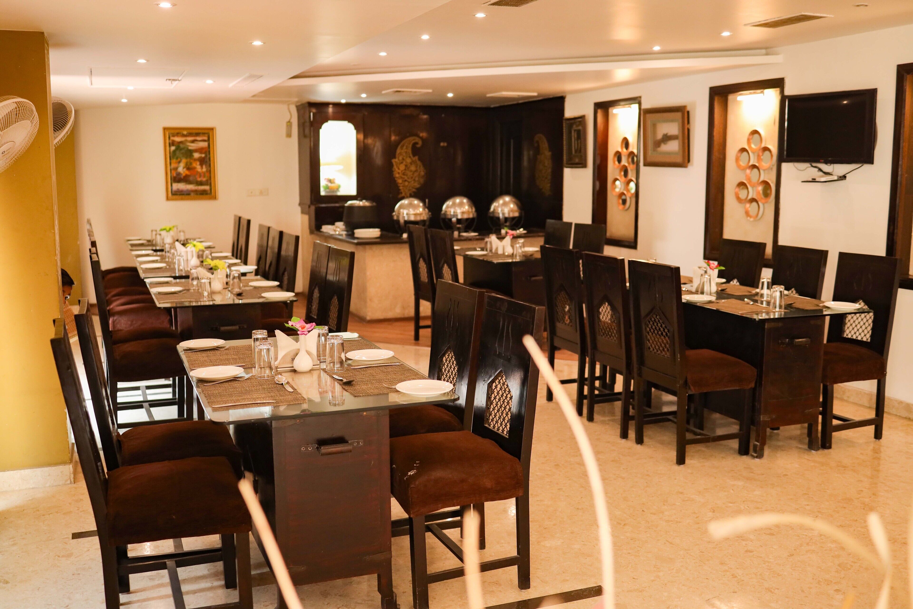 A restaurant with a long communal table, individual tables, and dark wooden chairs.