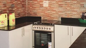 Ett kök med vita skåp, en spis och en kakelbeklädd vägg bakom arbetsbänken.