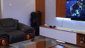 Ett modernt vardagsrum med en tv, en soffa i läder och en dekorativ taklampa.
