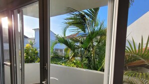 Una porta corredissa de vidre dona pas a un balcó amb vistes a un jardí i edificis veïnals.